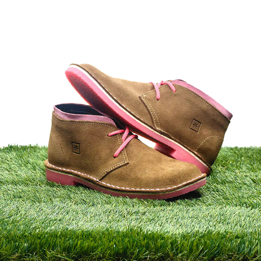 Brown shoes with pink soles on a grassy surface