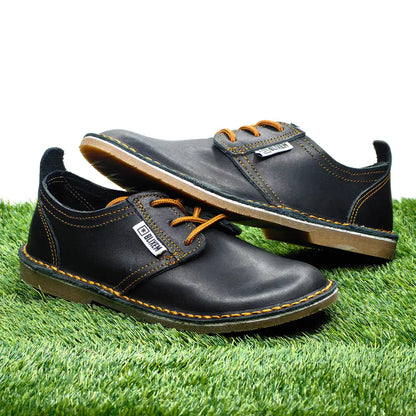 Pair of black leather shoes with copper gold accents on a grass background
