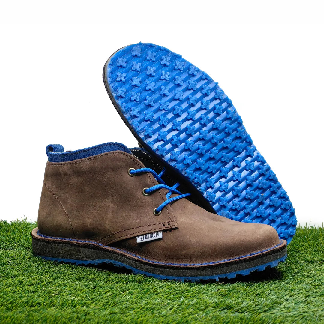 Brown leather boot with blue sole on grass