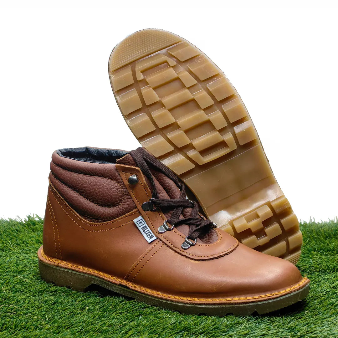 Red tan leather boot with a checkered sole on a grassy background
