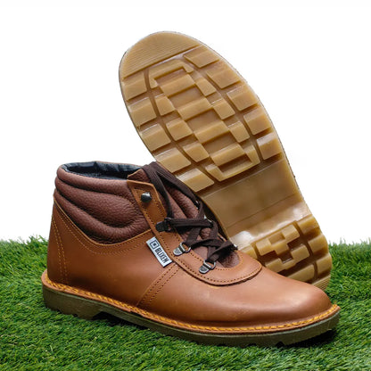 Red tan leather boot with a checkered sole on a grassy background