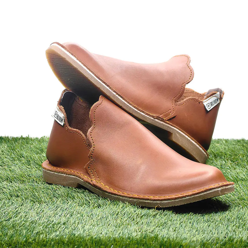 Pair of tan leather slipin on a grassy surface