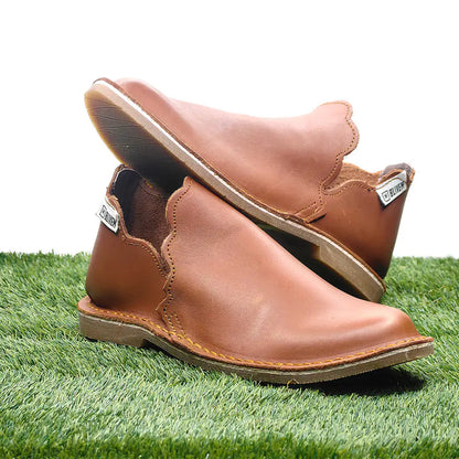 Pair of tan leather slipin on a grassy surface